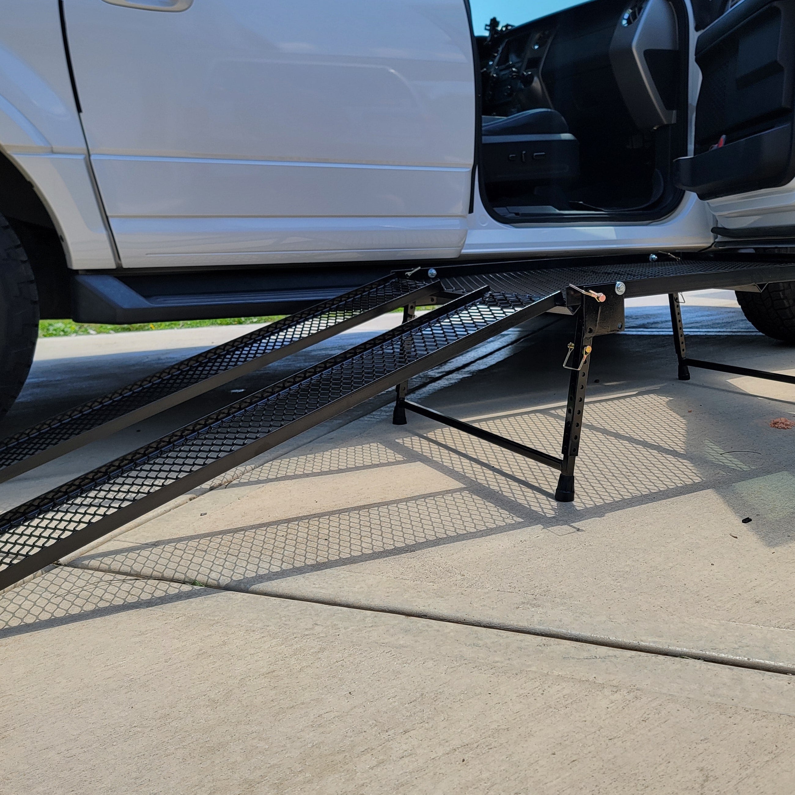 An adjustable height accessibility platform with telescoping and folding legs, and detachable ramps, placed in front of a vehicle to aid wheelchair users in transferring to the vehicle seat.
