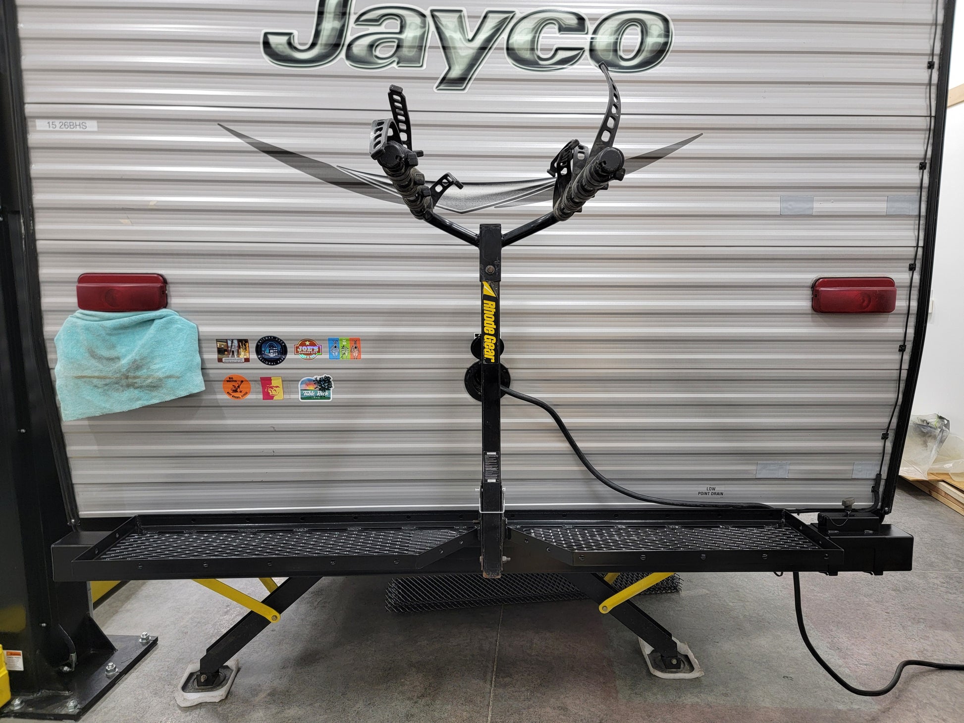 Black bike rack attached to a Jayco RV in a garage setting