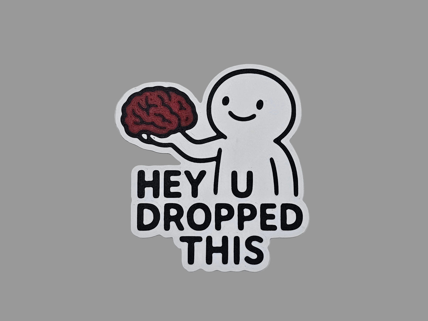 White, black, and red Hey You Dropped This brain magnet with smiling figure