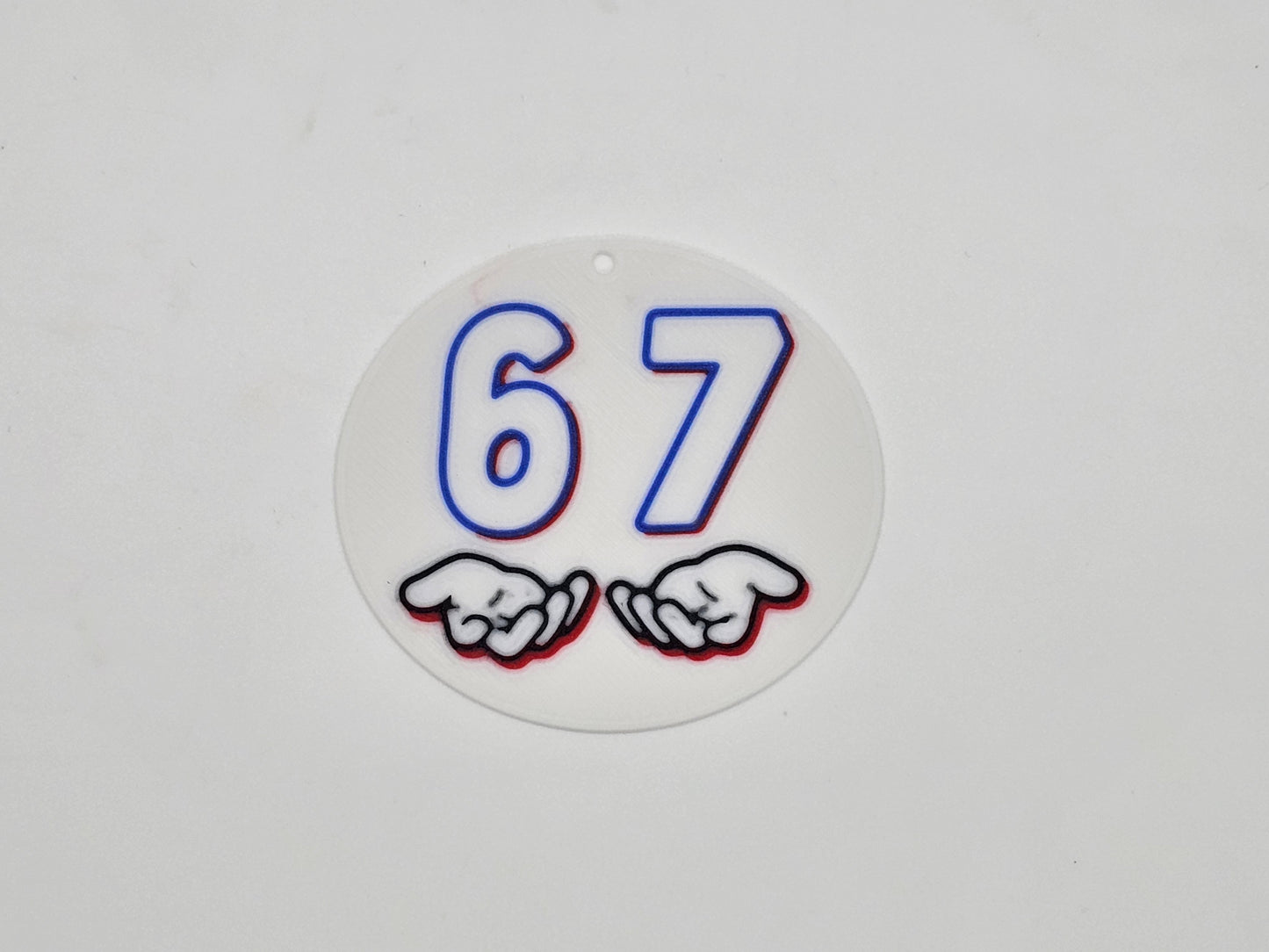Round white, blue, and red 67 hand gesture meme magnet