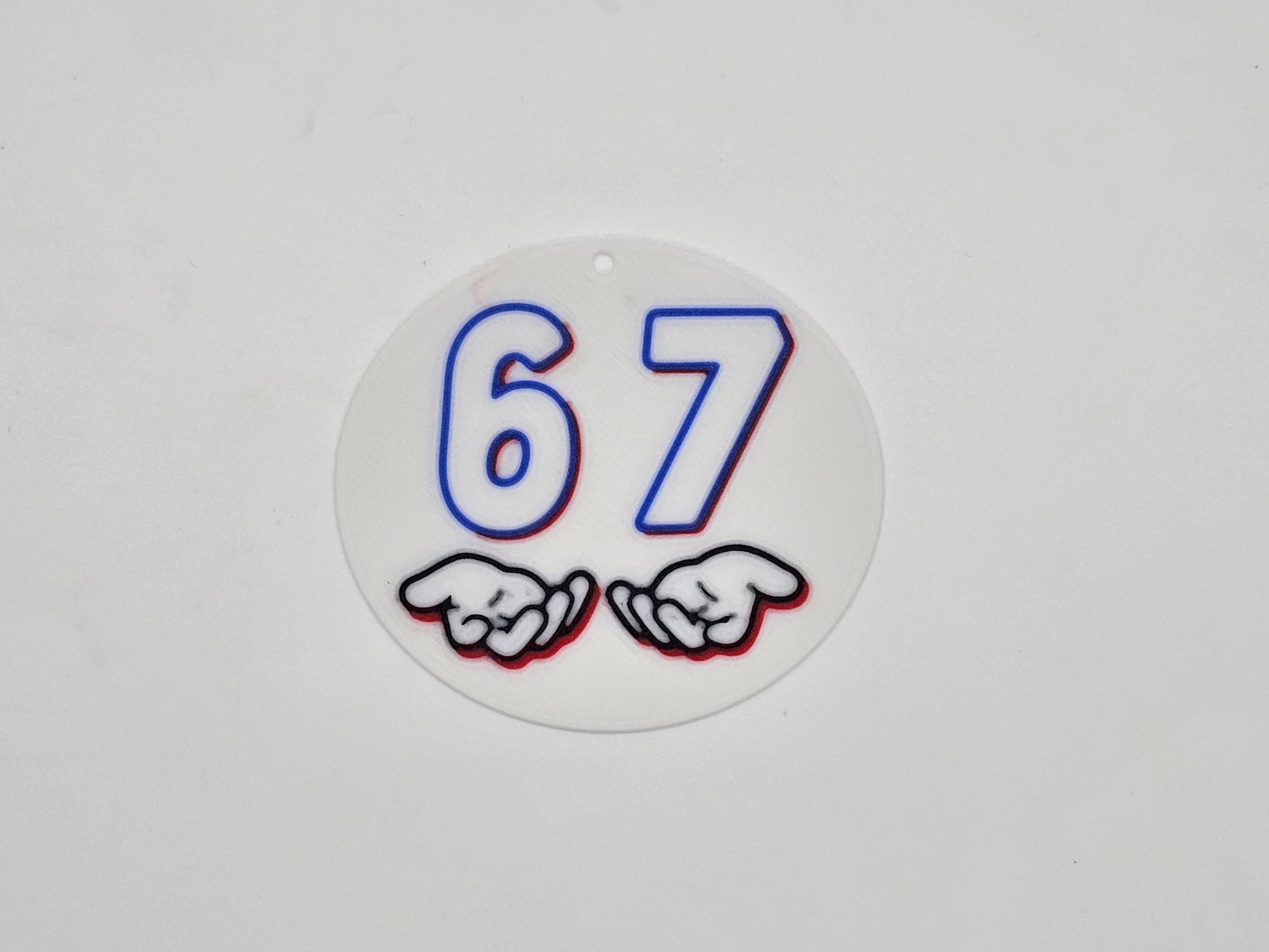 Round white, blue, and red 67 hand gesture meme magnet