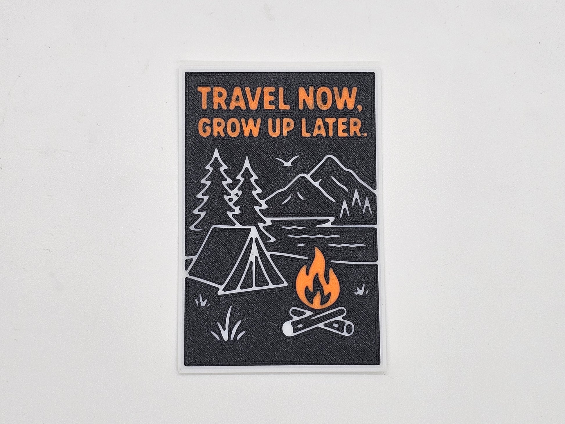 Black, orange, and gray Travel Now Grow Up Later camping magnet