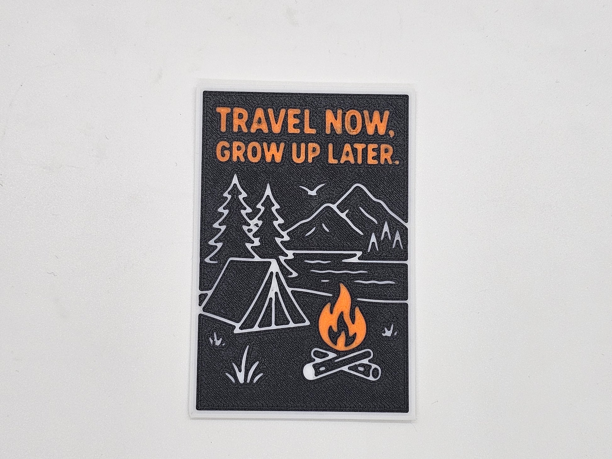 Black, orange, and white Travel Now Grow Up Later camping magnet