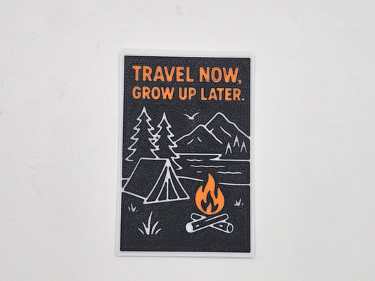 Black, orange, and white Travel Now Grow Up Later camping magnet