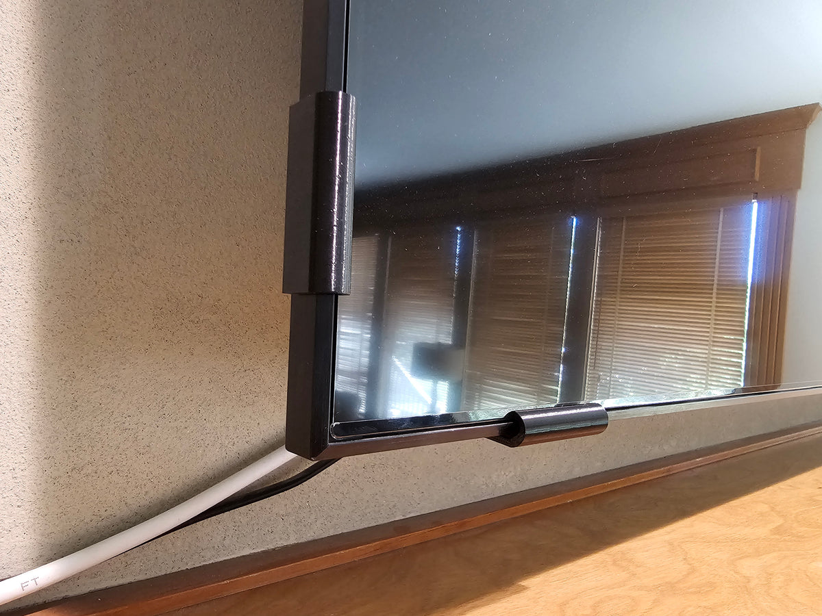 Black universal TV screen retention clips installed on the side and bottom of a television