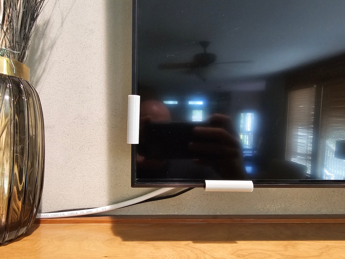 Two silver universal TV screen retention clips installed on a television