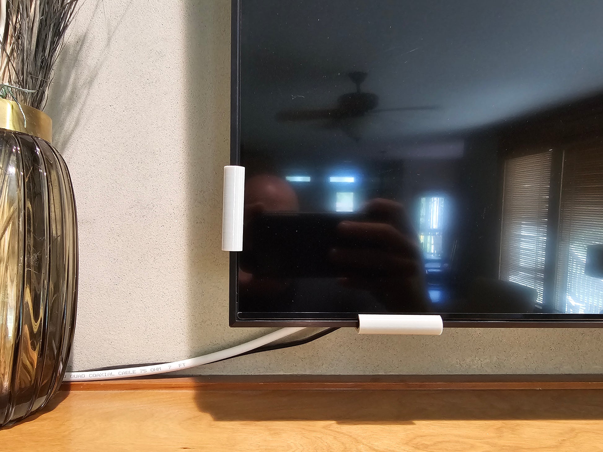Two silver universal TV screen retention clips installed on a television