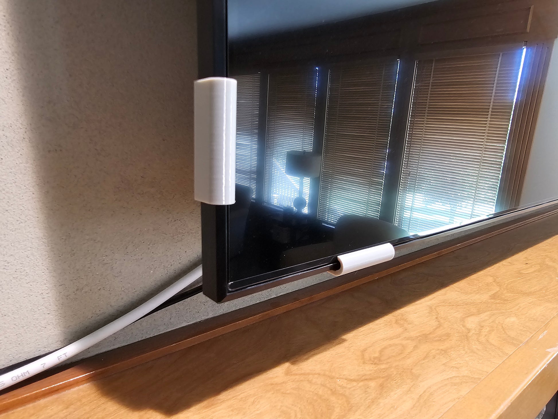 Silver universal TV screen retention clips installed on the side and bottom of a television